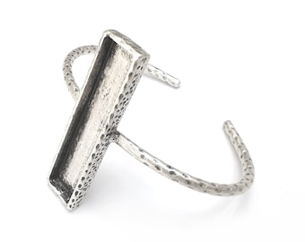 May include: A silver-toned cuff bracelet with a rectangular centerpiece. The bracelet has a textured, hammered appearance. The open design allows for easy wear. The rectangular centerpiece is approximately 1.5 inches long.