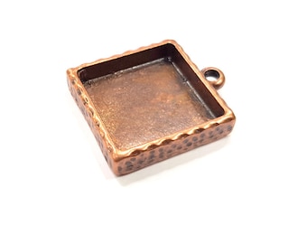 May include: A square copper pendant tray with a textured edge and a loop for hanging. The tray is designed for resin casting or other crafting projects.