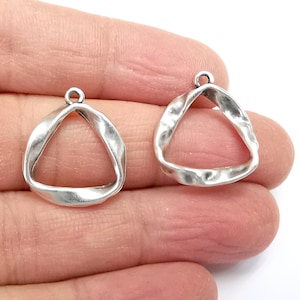May include: Two silver triangle shaped pendant charms with a textured finish. The charms have a hole at the top for attaching to a necklace or bracelet.