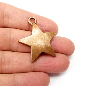May include: A gold-toned metal star charm with a loop at the top for attaching to jewelry or crafts.
