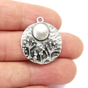 Puede incluir: Encanto de plata con un diseño redondo texturizado que presenta una luna en relieve y plantas estilizadas.