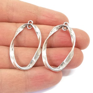 Puede incluir: Dos pendientes de aro ovalados de plata retorcidos con textura martillada.