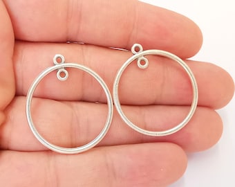 May include: Two silver-toned metal hoops with a small loop at the top. The hoops are approximately 5 cm in diameter.
