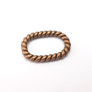 Op de afbeelding: Een koperkleurige ring met een gevlochten touwontwerp.