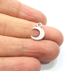 Puede incluir: Un amuleto de plata en forma de media luna con un bucle en la parte superior para sujetarlo a joyas u otras manualidades.