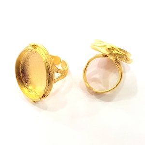 May include: Two gold-tone metal ring blanks with a round bezel setting. The bezel is smooth and has a slightly raised edge. The ring bands are simple and have a slightly textured finish.