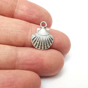 May include: Silver-toned seashell charm pendant. The charm is detailed with a textured, ribbed surface.