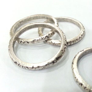 以下が含まれることがあります： 複雑なデザインが施された銀の指輪が4つ。指輪は重ねられています。