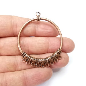 May include: Copper hoop earring with a decorative design and a loop at the top for hanging.