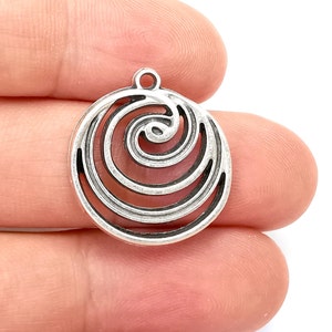 May include: Silver charm with a circular design featuring a spiral pattern.
