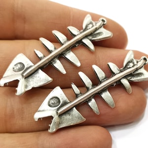 May include: Two silver-toned fish bone charms with a loop at the top for attaching to jewelry or other crafts.