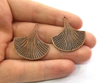 May include: Two copper-colored metal ginkgo leaf charms with a textured surface and a loop at the top for hanging.