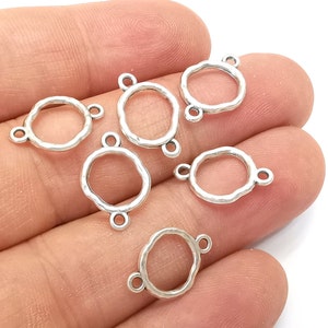 May include: Six silver-toned metal jump rings with a textured, hammered finish. Each ring has three loops for attaching jewellery components.