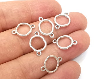 Puede incluir: Seis anillos de salto de metal plateados con un acabado texturizado martillado. Cada anillo tiene tres bucles para sujetar componentes de joyería.