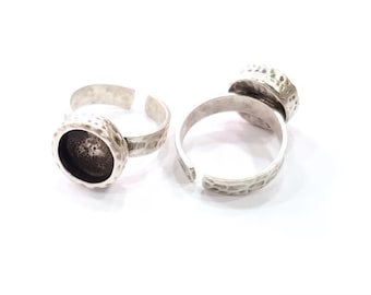 May include: Two silver adjustable rings with a round bezel setting for a cabochon stone. The rings have a hammered texture.