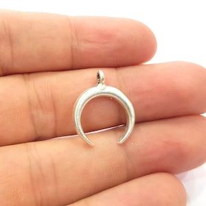 Puede incluir: Encanto de luna creciente de plata con un bucle para sujetarlo a un collar o pulsera.