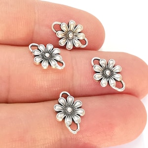 May include: Four silver-toned flower-shaped charms with a loop on each side. The charms are approximately 1 inch in diameter.