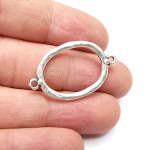 May include: Silver oval connector with two jump rings. The connector has a textured, hammered finish.