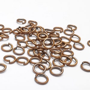May include: A pile of small, gold-colored jump rings. The rings are made of metal and are about 1/2 inch in diameter.