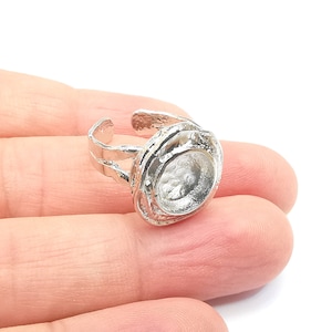 May include: Silver ring with a round, open setting. The ring is adjustable and has a textured, organic design.
