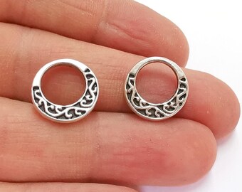 Op de afbeelding: Twee zilverkleurige metalen ringen met een decoratief, swirlend ontwerp. De ringen hebben een diameter van ongeveer 2,5 cm.