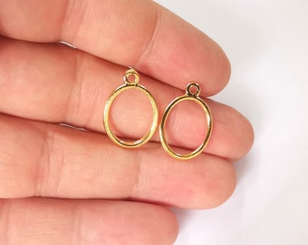 Puede incluir: Dos anillos de metal ovalados de color dorado con un pequeño bucle en la parte superior. Los anillos tienen un diámetro de aproximadamente 2,5 cm.