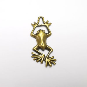 May include: A gold-toned metal frog charm with a loop at the top for hanging. The frog is in a sitting position with its legs outstretched.