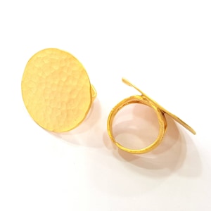 May include: Two gold-toned rings with a hammered texture. One ring is a flat circle and the other is a ring with a flat circle attached to it.