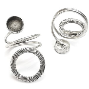 May include: Silver ring with a spiral design and a round bezel setting. The ring is made of twisted wire and has a smooth finish.