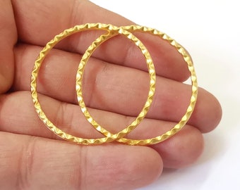 May include: Two gold-toned hoop earrings with a textured, wavy design.