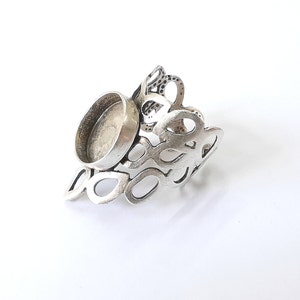 Può includere: Anello in argento con una montatura rotonda a becco aperto. La fascia dell'anello è realizzata con un design delicato e traforato.