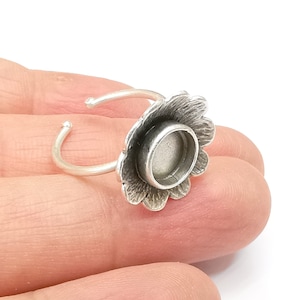 May include: Silver adjustable ring with a flower-shaped bezel for a round cabochon. The bezel is designed to hold a 12mm round cabochon.