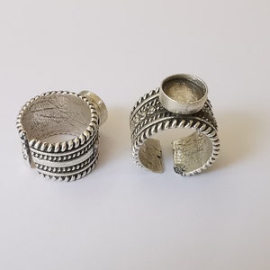 Puede incluir: Dos anillos de plata con un dise&ntilde;o decorativo. Un anillo tiene un engaste redondo y vac&iacute;o para una piedra o cabuj&oacute;n.