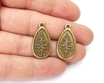 May include: Two antique gold-toned metal charms shaped like teardrops with a pine tree design.