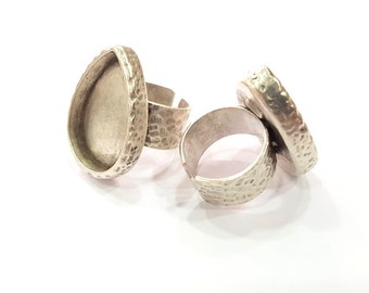 May include: Two silver rings with textured surfaces. One ring has a round bezel setting for a cabochon stone.