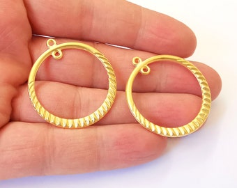 May include: Two gold-coloured metal hoops with a textured surface and a loop at the top. The hoops are approximately 5 cm in diameter.