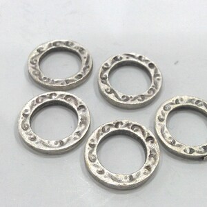 May include: Five silver-toned metal rings with an ornate design. The rings are all the same size and have a smooth, polished finish.