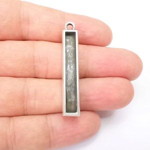 May include: Silver pendant with a rectangular open frame, perfect for adding a personal touch to jewelry projects.