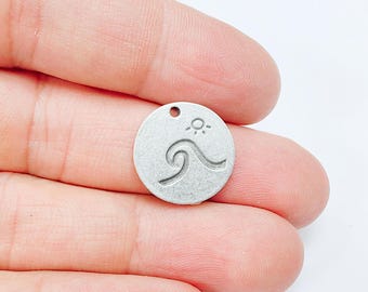 May include: Silver charm with a wave and sun design. The charm has a hole at the top for attaching to a necklace or bracelet.