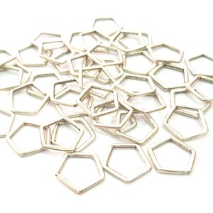 May include: A pile of silver-toned hexagonal jump rings. The rings are all the same size and shape, and they are arranged in a random pattern.