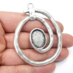 May include: Silver pendant with a spiral design and a round, open space for a cameo or other embellishment.
