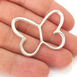 Peut inclure: Breloque en métal argenté en forme de papillon avec un double cœur. Le breloque est ouvert et a une finition lisse et polie.