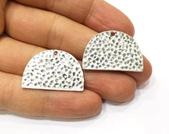 May include: Two silver half-circle metal charms with a hammered texture and a hole at the top for attaching to jewelry or other crafts.
