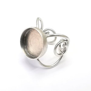May include: Silver ring with a round, open bezel setting. The ring band is made of twisted wire.