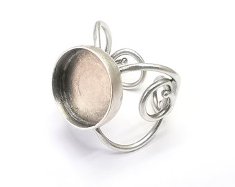 May include: Silver ring with a round, open bezel setting. The ring band is made of twisted wire.