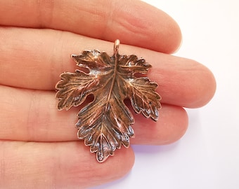 Op de afbeelding: Een koperkleurige metalen bladhanger met een gedetailleerd, gestructureerd ontwerp. Het blad heeft een lus aan de bovenkant om te bevestigen aan sieraden of andere knutselwerkjes.