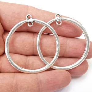 以下が含まれることがあります： ハンマーで叩いたような質感のシルバー製のフープピアス2個。上部にジャンプリングが付いています。