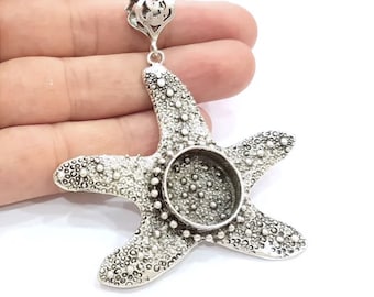 May include: Silver starfish pendant with a round bezel for a cabochon. The pendant has a textured surface and a bail for attaching to a chain.