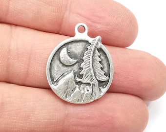 May include: Silver charm featuring a detailed design of a mountain range, a pine tree, and a crescent moon.