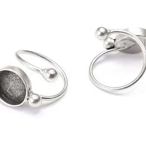 May include: Silver ring with a round bezel setting and two small balls on the band.